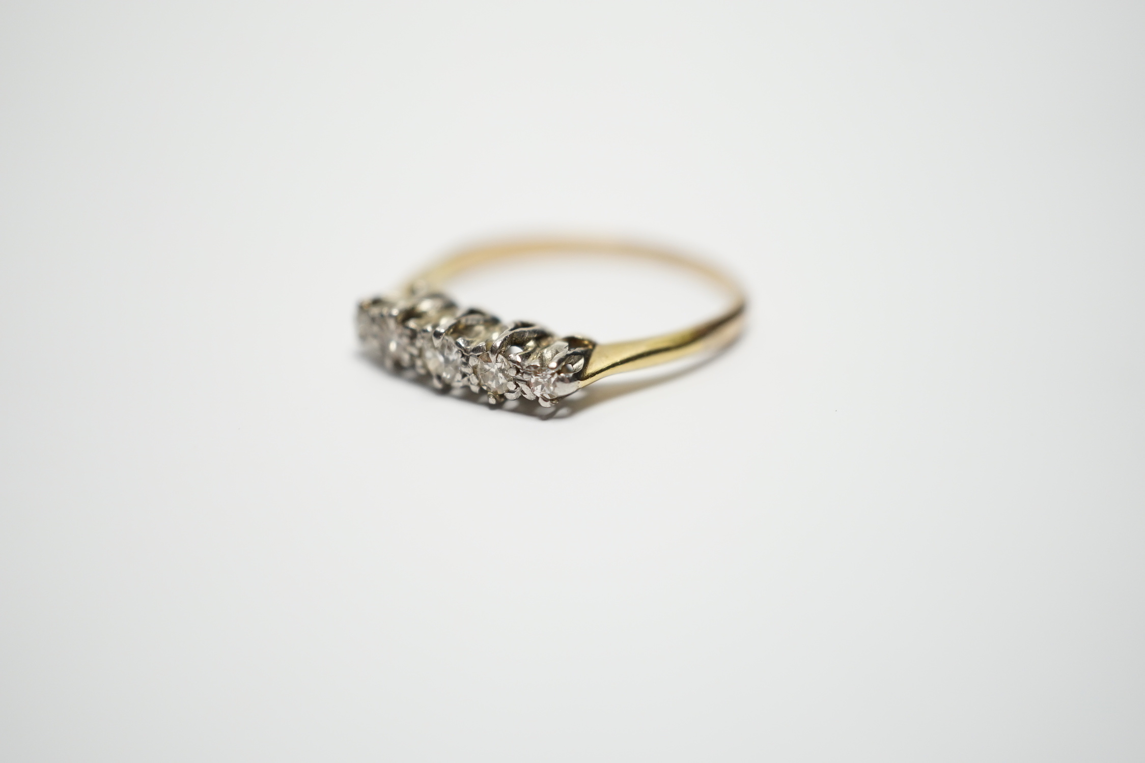 A yellow metal and graduated five stone diamond set half hoop ring, size M, gross weight 2 grams.